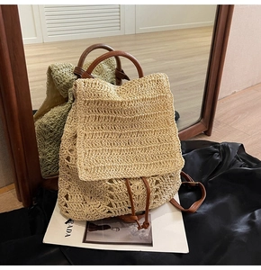 Detail of woven straw backpack with brown leather straps and drawstring closure