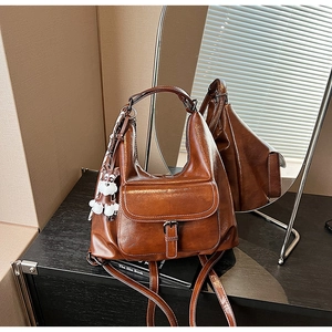 Detail of dark brown leather tote featuring a retro buckled pocket and a cute puppy charm