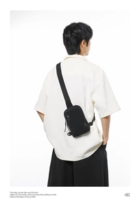 Back view of a black minimalist nylon crossbody chest bag worn by a model