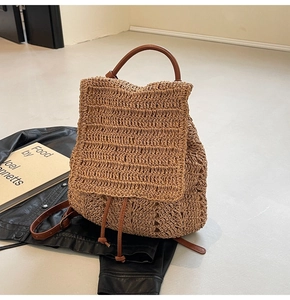 Detail of straw woven backpack featuring brown leather straps and drawstring closure