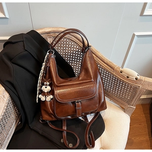 Close-up of vintage brown leather backpack texture with dog charm on a wooden chair