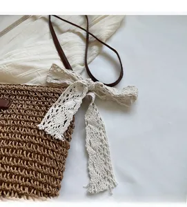 Detail of woven straw bucket bag featuring white lace bow and brown leather shoulder strap