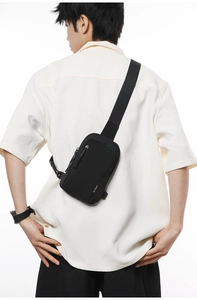Rear view of a black nylon crossbody chest bag with adjustable strap on a model