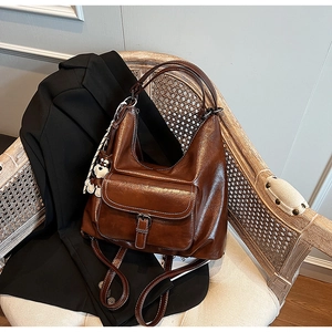 Detail of vintage brown wax leather backpack with front pocket and panda charm