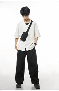 Detail of waffle textured off-white shirt paired with a black nylon crossbody chest bag