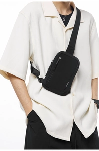 Detail of black nylon crossbody bag featuring silver zippers and adjustable wide strap