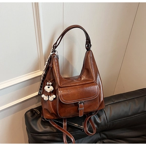 Detail of dark brown vintage leather tote with decorative scarf and cute dog pendant