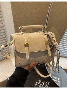 Borsa a tracolla beige chic con dettagli dorati e ciondolo a nappa caratteristico