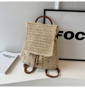 Detail of woven straw backpack featuring brown leather straps and drawstring closure