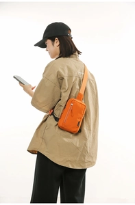 Detailed view of the bright orange nylon crossbody chest bag on a female model