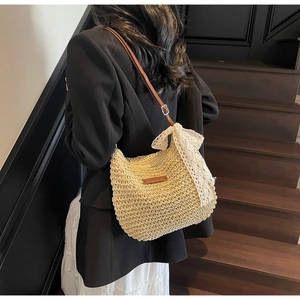 Detail of woven straw shoulder bag with a large white lace bow and brown leather strap