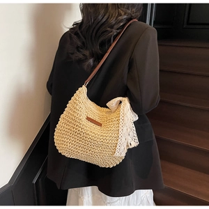Detail of beige woven straw bucket bag with large white lace bow and leather strap