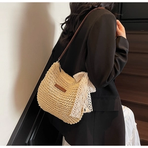 Detail of hand-woven straw crossbody bag with white lace bow and brown leather strap