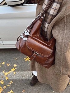 Brown vintage leather tote bag with dog charm and scarf in outdoor street style
