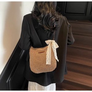 Detail of woven straw crossbody bag with white lace bow on elegant wooden background