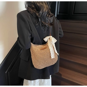 Detail of woven straw bag with a large white lace bow and leather patch on back