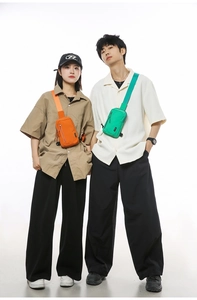 Detail of compact nylon crossbody bags in orange and green with multi-zipper design