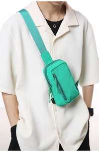Bright green nylon crossbody bag shown on model with multiple zipper compartments