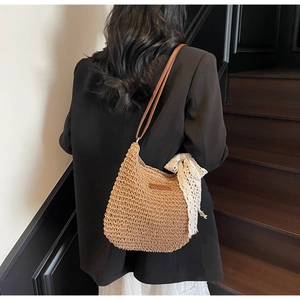 Close-up of woven straw bucket bag featuring a leather strap and delicate lace ribbon
