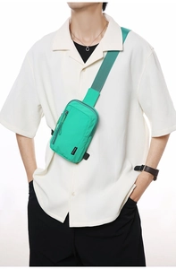 Detail of adjustable green nylon strap and black woven logo on the crossbody bag