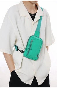 Detail of mint green nylon crossbody bag showing the zipper pocket and fabric texture
