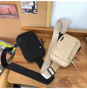 Detail of black and beige nylon crossbody bags on a wooden desk for travel