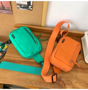 Detail of vibrant green and orange nylon crossbody bags with smooth front zippers