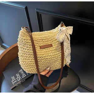 Detail of woven straw bucket bag with brown leather straps and a white lace bow detail