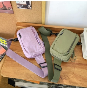 Detail view of nylon crossbody bags in lilac and olive green on a wooden table