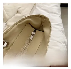 Detail view of woven straw tote bag featuring smooth fabric lining and silver metal zipper