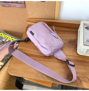 Detail of light purple nylon crossbody bag featuring front zipper and adjustable strap