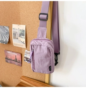 Close-up of a lavender nylon crossbody bag with dual zippers and a wide adjustable strap