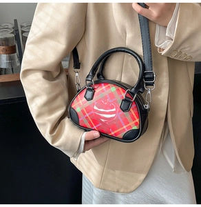Detailansicht einer roten Mini-Handtasche mit Karomuster und Herz-Graffiti-Motiv