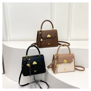 Close-up of three retro square bags with gold animal clasps in brown, black, and cream