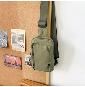 Detailed view of army green nylon crossbody bag with zipper pockets and adjustable strap