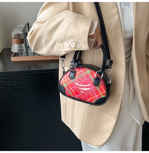 Detail einer Vintage-Karo-Handtasche mit Herzgrafik, getragen von einem Model in Beige