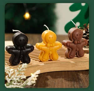 Three gingerbread man candles in various brown shades on wooden tray with festive decor