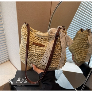 Detail of hand-woven straw bag featuring a white lace bow and brown leather strap
