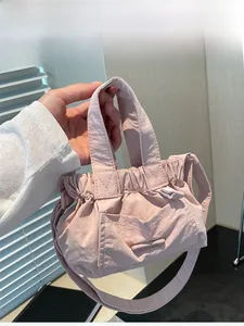 Detail of pink pleated bucket bag with dual handles and adjustable shoulder strap