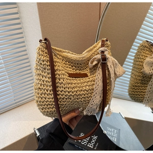 Detail of woven straw shoulder bag with lace bow, leather strap and secure zipper closure