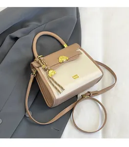 Close-up of beige and brown crossbody bag with a golden bear buckle and leather charm