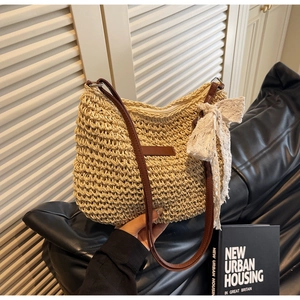 Detailed texture of white woven straw bag with dark brown leather strap and lace bow