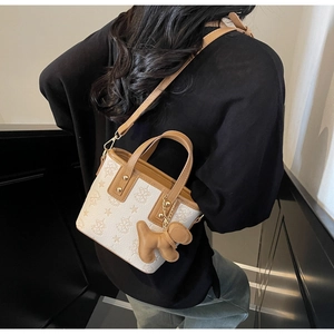 Mini sac seau crème chic avec motifs gaufrés et breloque chiot marron sur le mannequin
