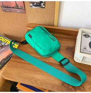 Detailed close-up of neon green nylon crossbody bag with dual zippers on a wooden desk