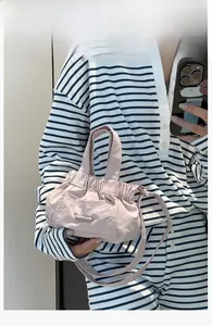 Macro view of mini light pink pleated nylon tote bag with pocket and shoulder strap