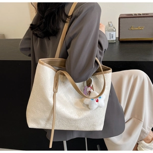Detail of embossed Chinese characters on cream tote bag with star plush pendant
