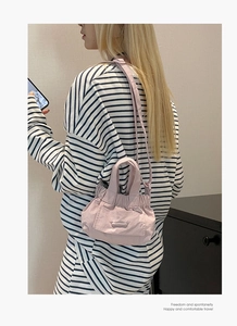 Close-up of a pink mini nylon drawstring bucket bag worn by a model in a casual setting