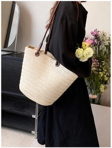 Detail shot of the cream woven tote bag with brown straps and fine straw texture