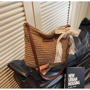 Detailed view of straw bucket bag featuring a white lace bow and brown leather strap