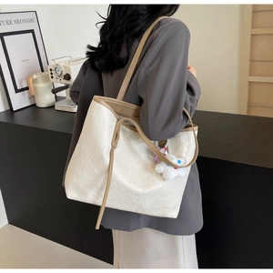 Detail of large tote bag featuring embossed mahjong pattern and plush doll accessory